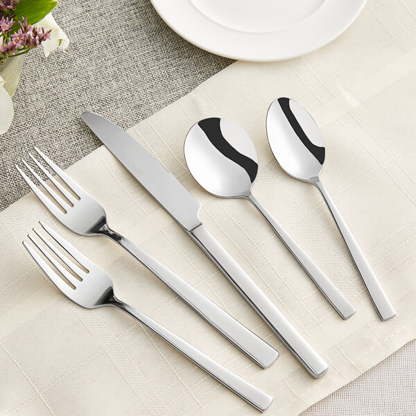 A five-piece set of stainless steel flatware including two forks, a knife, and two spoons.
