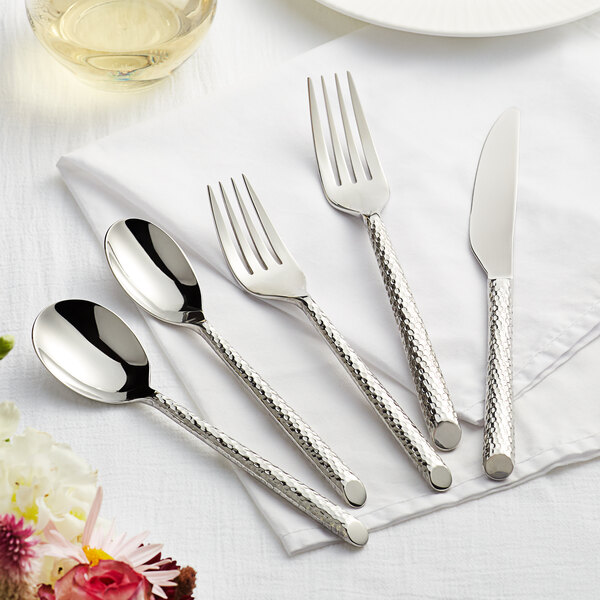 A five-piece set of stainless steel flatware with textured handles, including two spoons, two forks, and a knife.