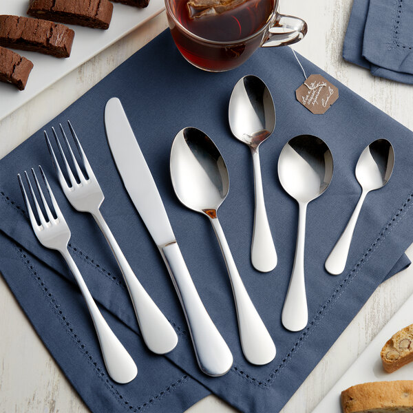 A five-piece set of Acopa Vernon 18/0 stainless steel heavy weight flatware displayed on a blue napkin.