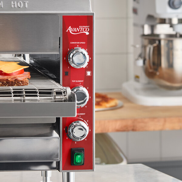 A stainless steel Avantco countertop ventless radiant electric conveyor oven with a 14-inch wide belt, shown toasting a sandwich.