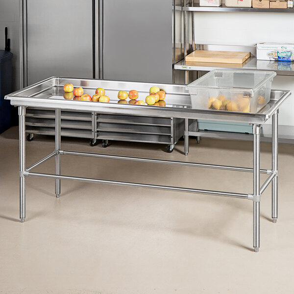 An Advance Tabco stainless steel sorting table with apples on it.