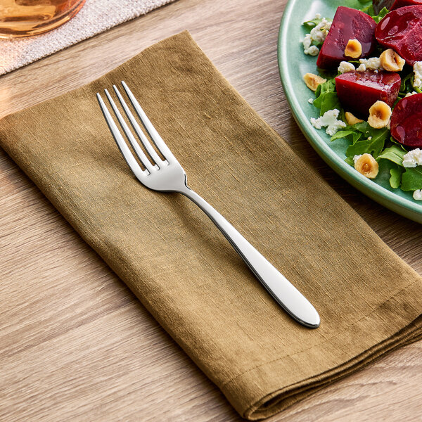 A stainless steel salad or dessert fork placed on a folded brown napkin.