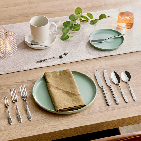 A set of stainless steel salad or dessert forks arranged on a dining table with other tableware.