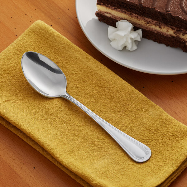 A stainless steel dessert spoon placed on a folded yellow napkin.