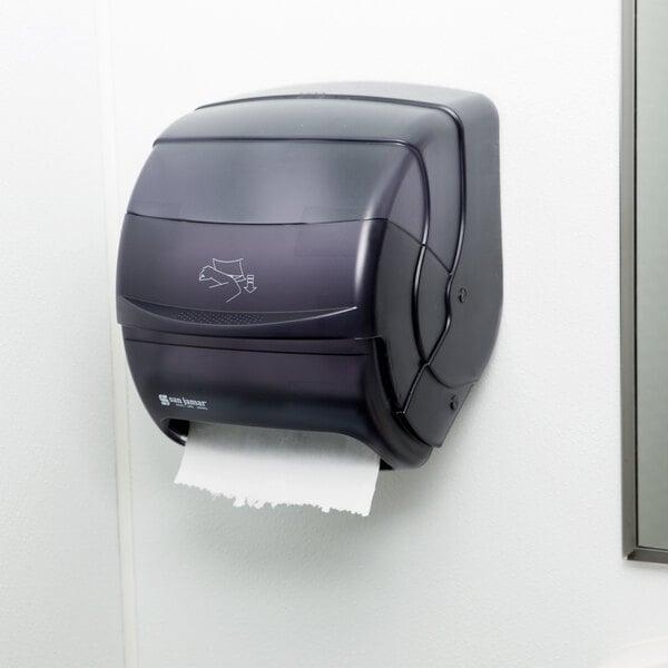 A black San Jamar Integra paper towel dispenser on a white wall.