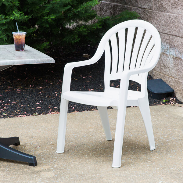 A Grosfillex Pacific White fanback stacking resin armchair on a concrete patio.