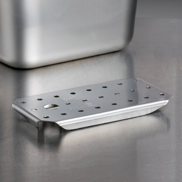 A stainless steel Vollrath false bottom tray with holes.