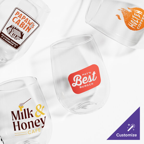 Four clear stemless wine glasses are shown, each featuring a different colorful custom logo or design printed on the front.