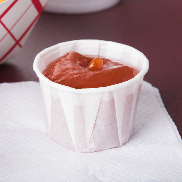 A Solo paper portion cup filled with red liquid sitting on a napkin.