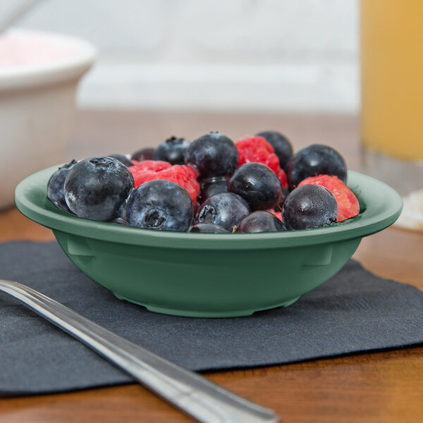 A black round GET SuperMel bowl filled with blueberries and raspberries on a table.