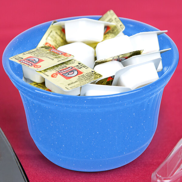 A Tablecraft blue speckle cast aluminum bowl on a counter with white yogurt packets in it.