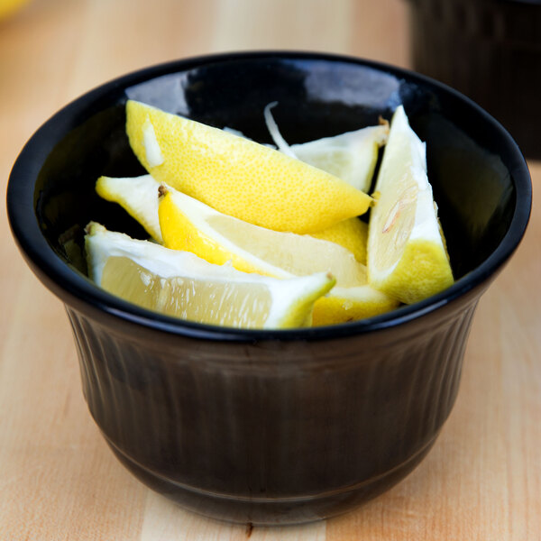 A Tablecraft black cast aluminum bowl of lemon wedges on a table.