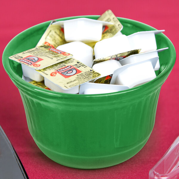 A green Tablecraft metal bowl filled with candy on a hotel buffet counter.