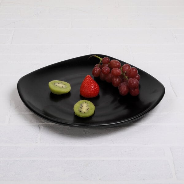 A black Elite Global Solutions square melamine plate with kiwi and strawberries on it.