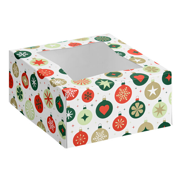 A square bakery box with a clear window on top, decorated with a festive ornament pattern in red, green, and gold colors.