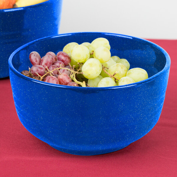 A Tablecraft blue speckle fruit bowl filled with grapes on a table.