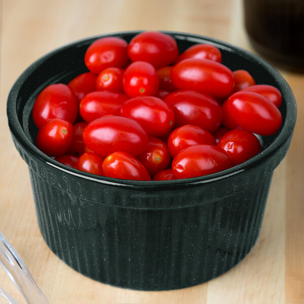 A Tablecraft hunter green and white speckled cast aluminum souffle bowl filled with cherry tomatoes on a counter.