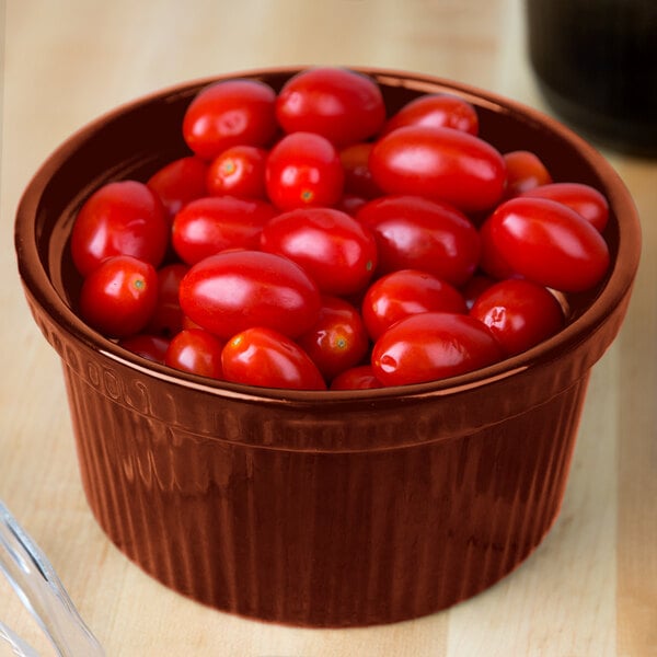 A Tablecraft copper cast aluminum souffle bowl with a bowl of cherry tomatoes.