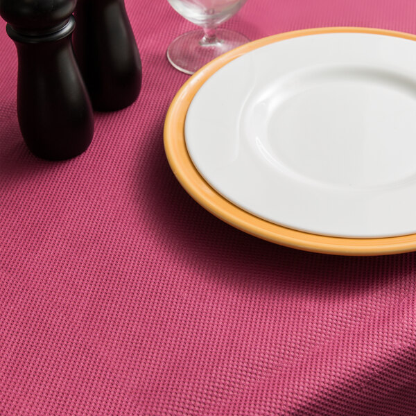 A plate and salt and pepper shakers on a burgundy table with a 54" x 54" Burgundy Tissue / Poly Table Cover.