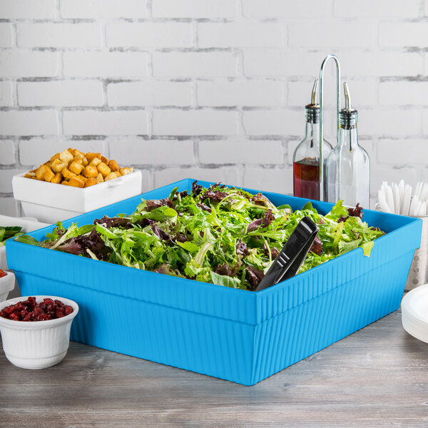 A Tablecraft sky blue square bowl filled with a salad on a table in a salad bar.