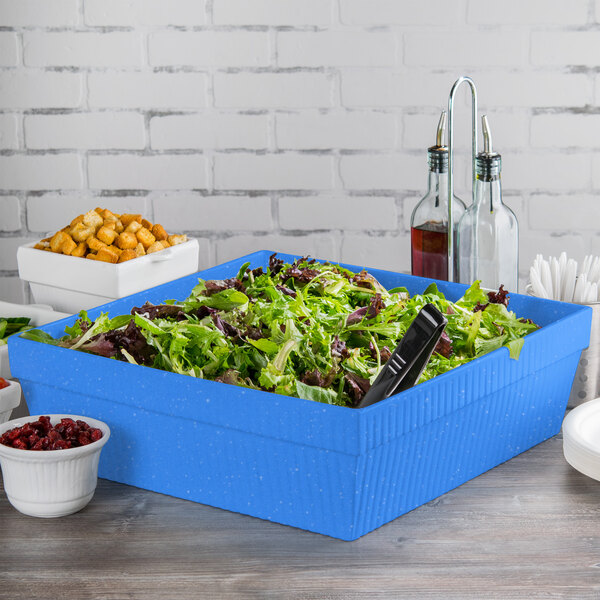A Tablecraft blue speckle cast aluminum square bowl on a table with a blue container of salad inside.
