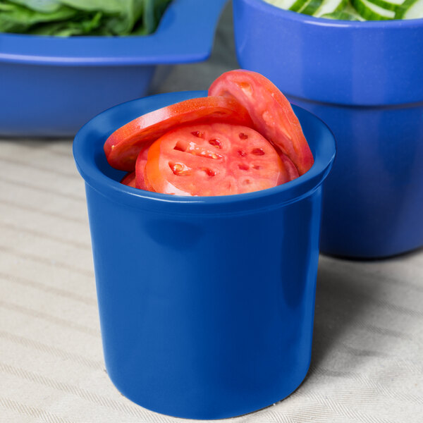 A Tablecraft cobalt blue cast aluminum condiment bowl filled with sliced tomatoes on a counter.