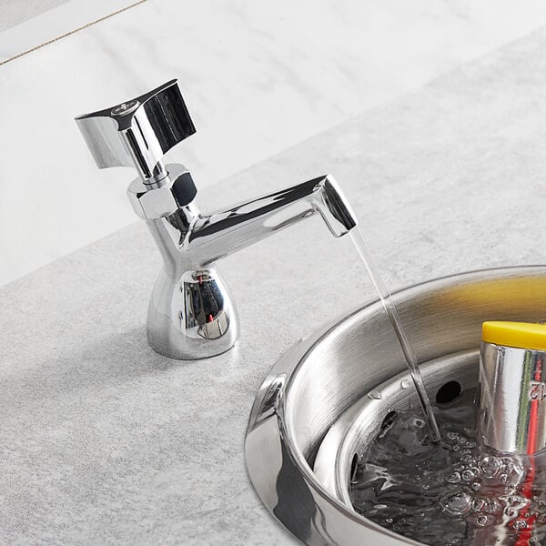 A Regency dipper well faucet running water into a metal sink.