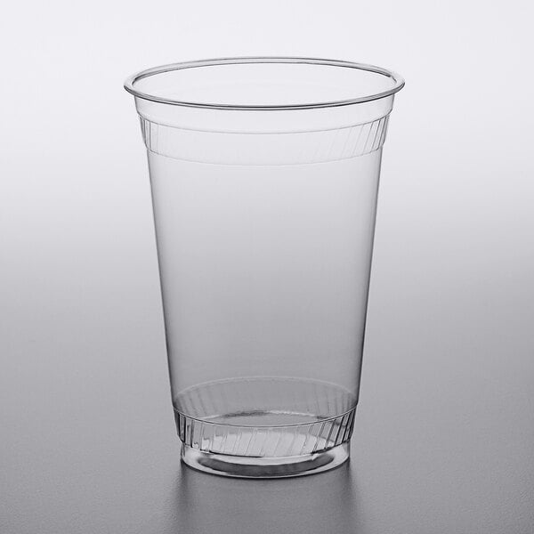 A Fabri-Kal clear plastic cup with a lid on a gray surface.