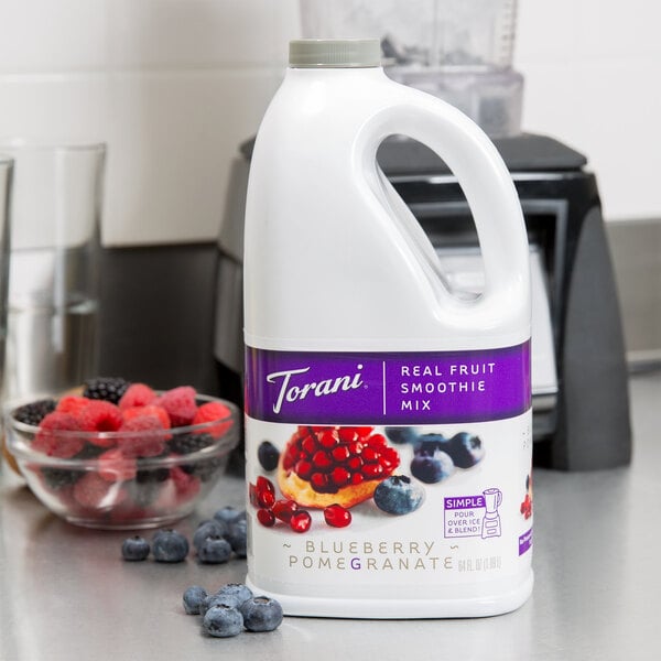 A white jug of Torani Blueberry Pomegranate Fruit Smoothie Mix with a purple label.