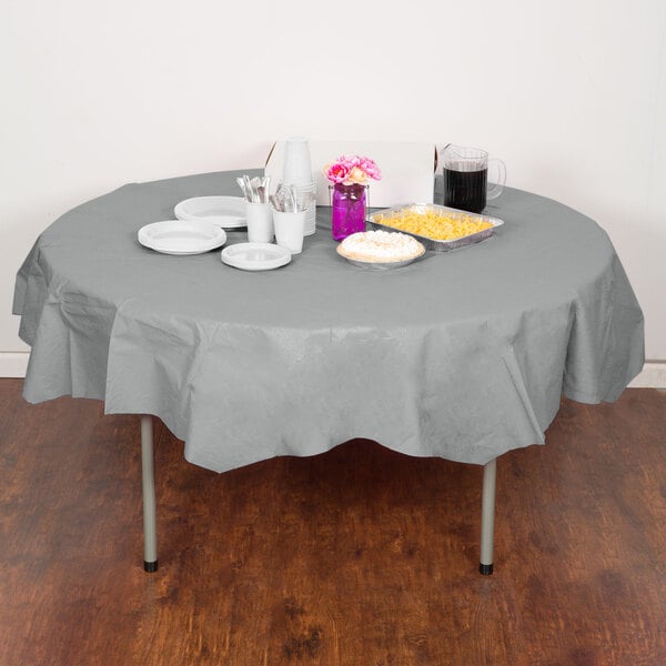 A table with a Shimmering Silver OctyRound table cover with food and drinks on it.