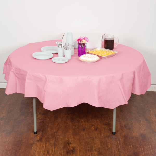 A table with a Classic Pink OctyRound table cover, plates, and cups on it.