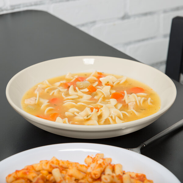 A Diamond Ivory melamine bowl with soup and noodles on a table.