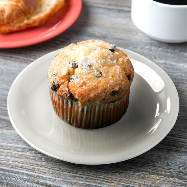 A Diamond Ivory melamine plate with a muffin on it on a counter.