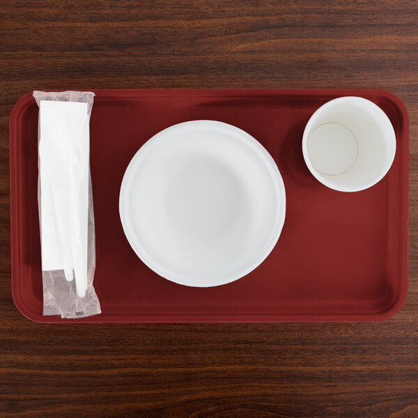 A red rectangular Cambro tray with a bowl and a cup and a napkin.