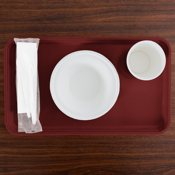 A red Cambro rectangular tray with a bowl and a cup and a napkin on it.