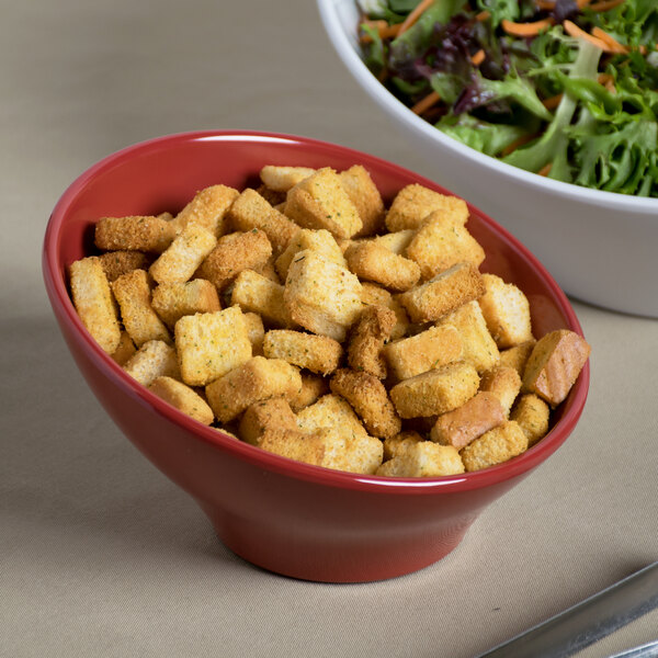 An Elite Global Solutions cranberry melamine bowl filled with salad and croutons.