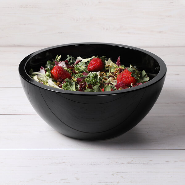 An Elite Global Solutions black melamine bowl filled with salad and strawberries.