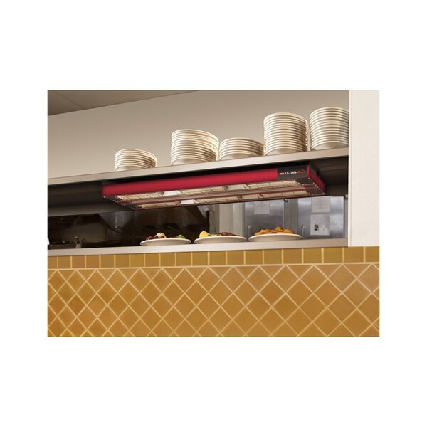 A shelf of stacked plates being warmed by a Hatco dual ceramic infrared strip warmer.