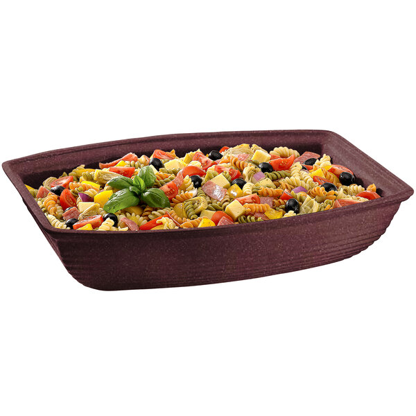 A maroon rectangular cast aluminum bowl with salad and vegetables on a table.