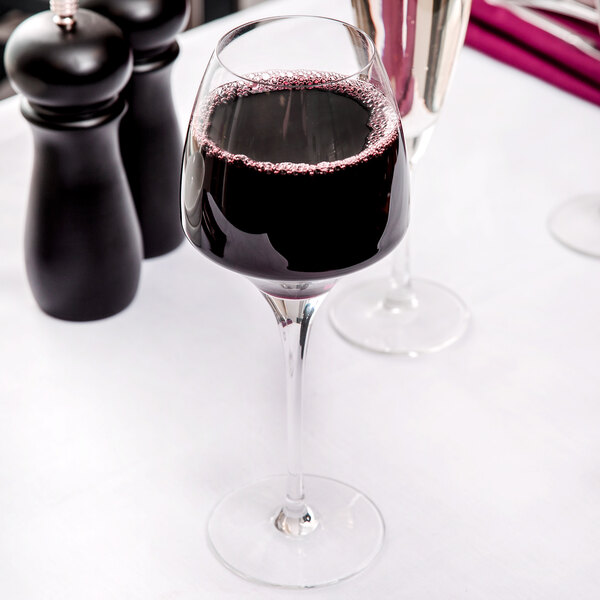 A Chef & Sommelier wine glass filled with red wine on a table.