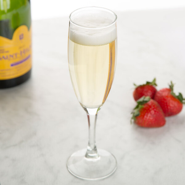 A close-up of an Arcoroc flute glass of champagne with strawberries.
