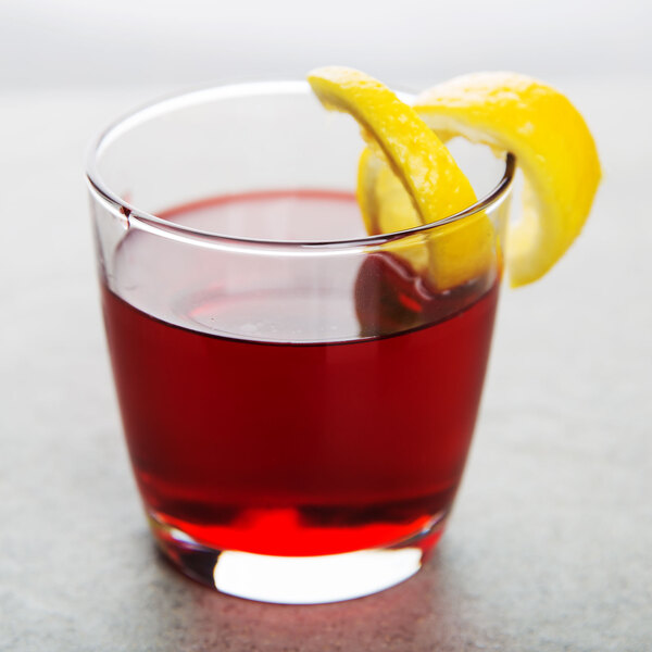 A customizable Arcoroc old fashioned glass filled with red liquid and garnished with a lemon wedge.