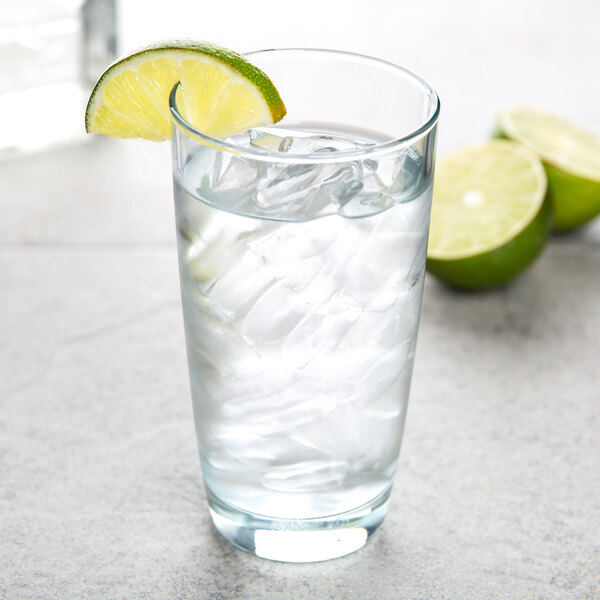 An Arcoroc highball glass filled with water, ice, and a slice of lime.