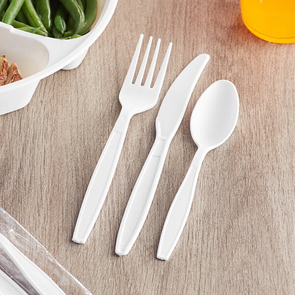 A Visions wrapped white plastic fork, spoon, and knife pack on a table.