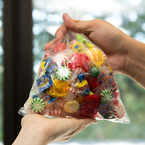 A hand holding a LK Packaging plastic candy bag full of candy.