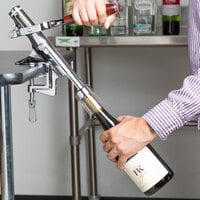 Hand pressing handle on stainless steel counter mount corkscrew down into wine cork
