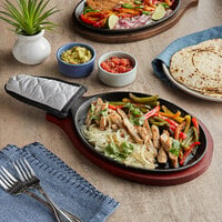 Choice 9 1/4 inch x 7 inch Oval Pre-Seasoned Cast Iron Fajita Skillet with Mahogany Finish Wood Underliner and Grey Silicone Coated Handle Cover