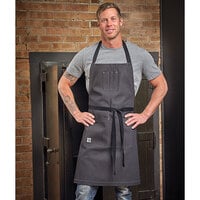Mercer Culinary M63206DEN Metro Edge® Scout Gray Customizable 65/35 Cotton/Poly Bib Apron with Adjustable Straps, Black Webbing, and 3 Pockets - 34 inchL x 29 3/4 inchW