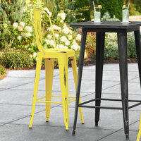 Lancaster Table & Seating Alloy Series Distressed Yellow Metal Indoor / Outdoor Industrial Cafe Barstool with Vertical Slat Back and Drain Hole Seat