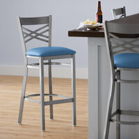 Lancaster Table & Seating Clear Coat Finish Cross Back Bar Stool with 2 1/2 inch Blue Vinyl Padded Seat - Detached
